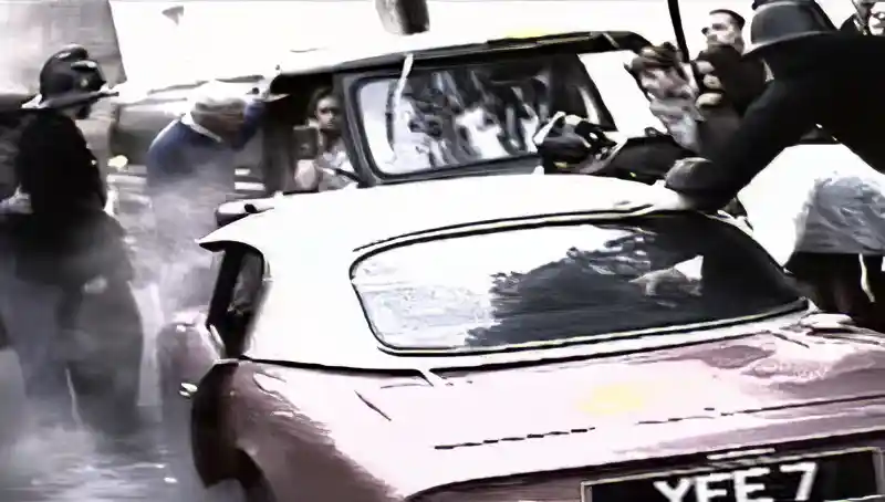 Car crash scene with onlookers gathered around a vehicle in the Free As A Bird video